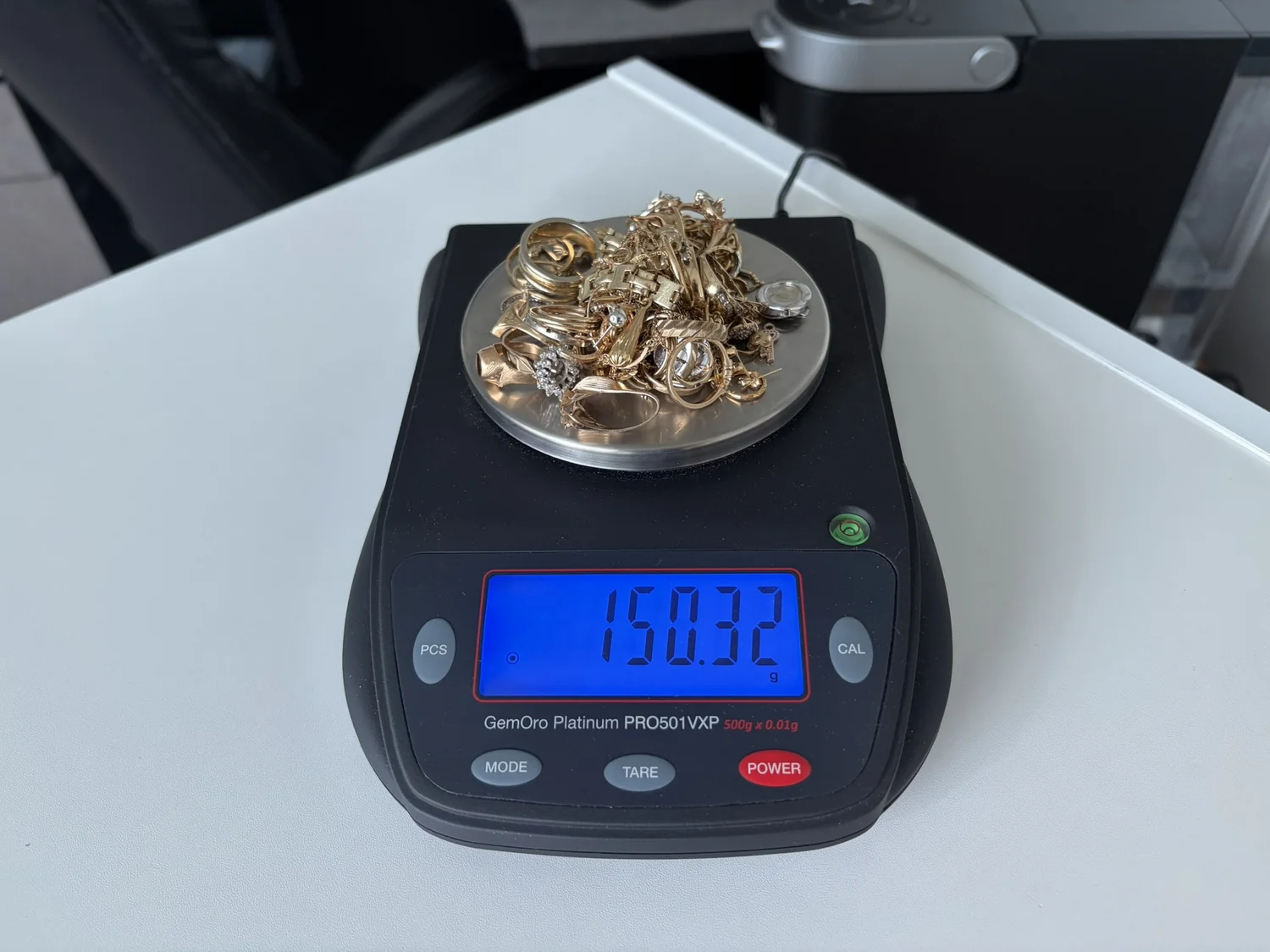 A mixed lot of gold jewellery on the counter scale reading 150.32 grams